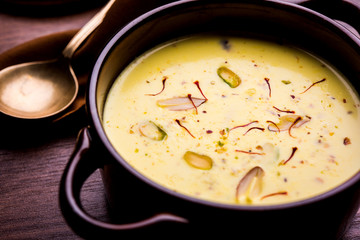 Basundi Or Rabri is an Indian sweet popular in Gujarat and Maharashtra. It is a sweetened condensed milk. Garnished with Dry fruits and Saffron. Served in a bowl over moody background. Selective focus