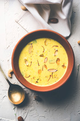 Basundi Or Rabri is an Indian sweet popular in Gujarat and Maharashtra. It is a sweetened condensed milk. Garnished with Dry fruits and Saffron. Served in a bowl over moody background. Selective focus
