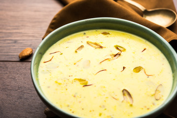 Basundi Or Rabri is an Indian sweet popular in Gujarat and Maharashtra. It is a sweetened condensed milk. Garnished with Dry fruits and Saffron. Served in a bowl over moody background. Selective focus