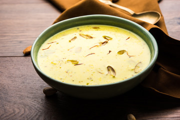 Basundi Or Rabri is an Indian sweet popular in Gujarat and Maharashtra. It is a sweetened condensed milk. Garnished with Dry fruits and Saffron. Served in a bowl over moody background. Selective focus