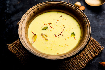 Basundi Or Rabri is an Indian sweet popular in Gujarat and Maharashtra. It is a sweetened condensed milk. Garnished with Dry fruits and Saffron. Served in a bowl over moody background. Selective focus