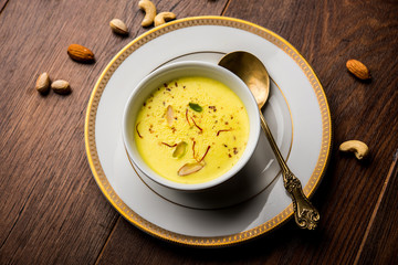 Basundi Or Rabri is an Indian sweet popular in Gujarat and Maharashtra. It is a sweetened condensed milk. Garnished with Dry fruits and Saffron. Served in a bowl over moody background. Selective focus
