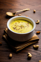 Basundi Or Rabri is an Indian sweet popular in Gujarat and Maharashtra. It is a sweetened condensed milk. Garnished with Dry fruits and Saffron. Served in a bowl over moody background. Selective focus