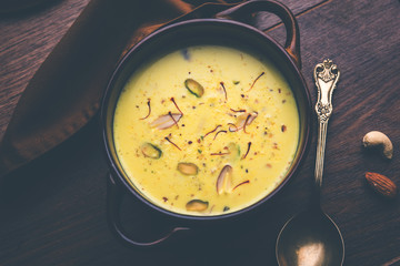Basundi Or Rabri is an Indian sweet popular in Gujarat and Maharashtra. It is a sweetened condensed milk. Garnished with Dry fruits and Saffron. Served in a bowl over moody background. Selective focus