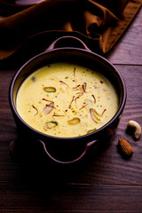 Basundi Or Rabri is an Indian sweet popular in Gujarat and Maharashtra. It is a sweetened condensed milk. Garnished with Dry fruits and Saffron. Served in a bowl over moody background. Selective focus