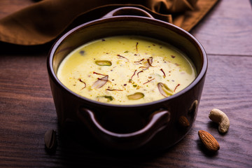 Basundi Or Rabri is an Indian sweet popular in Gujarat and Maharashtra. It is a sweetened condensed milk. Garnished with Dry fruits and Saffron. Served in a bowl over moody background. Selective focus