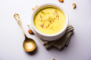 Basundi Or Rabri is an Indian sweet popular in Gujarat and Maharashtra. It is a sweetened condensed milk. Garnished with Dry fruits and Saffron. Served in a bowl over moody background. Selective focus