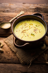 Basundi Or Rabri is an Indian sweet popular in Gujarat and Maharashtra. It is a sweetened condensed milk. Garnished with Dry fruits and Saffron. Served in a bowl over moody background. Selective focus