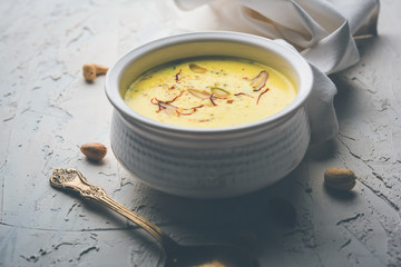 Basundi Or Rabri is an Indian sweet popular in Gujarat and Maharashtra. It is a sweetened condensed milk. Garnished with Dry fruits and Saffron. Served in a bowl over moody background. Selective focus