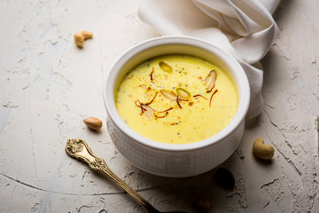 Basundi Or Rabri is an Indian sweet popular in Gujarat and Maharashtra. It is a sweetened condensed milk. Garnished with Dry fruits and Saffron. Served in a bowl over moody background. Selective focus