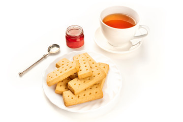 A photo of Scottish shortbread butter cookies on a white background with a cup of tea, jam, and copy space