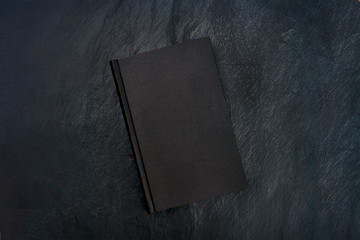 A photo of a black book, shot from the top on a dark background with a place for text