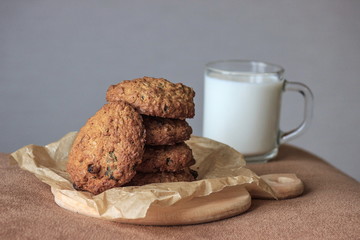Cap of milk with oat cookies with raisins. Homemade food. Grey background