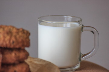Cap of milk with oat cookies with raisins. Homemade food. Grey background. Focused on the cap