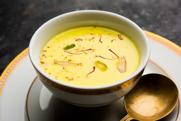 Basundi Or Rabri is an Indian sweet popular in Gujarat and Maharashtra. It is a sweetened condensed milk. Garnished with Dry fruits and Saffron. Served in a bowl over moody background. Selective focus