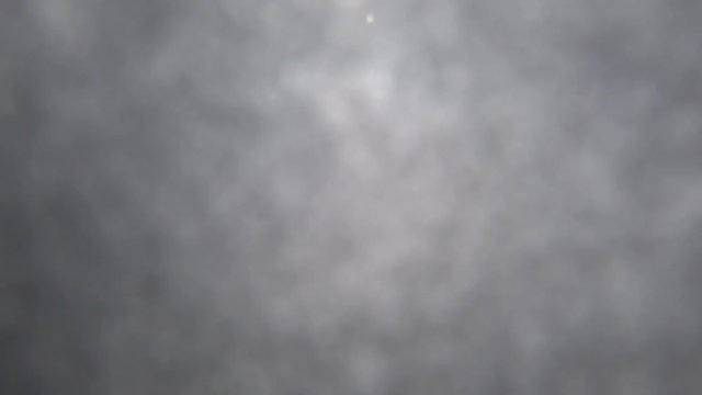 a man on a snowmobile jumping from a snow boost and fills up with snow in the camera. against the blue sky with clouds. super 4K video with snow sprays and whirlwinds