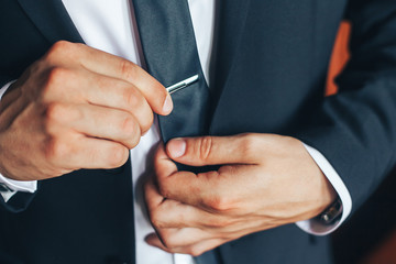 Man in a classic suit straightens his tie