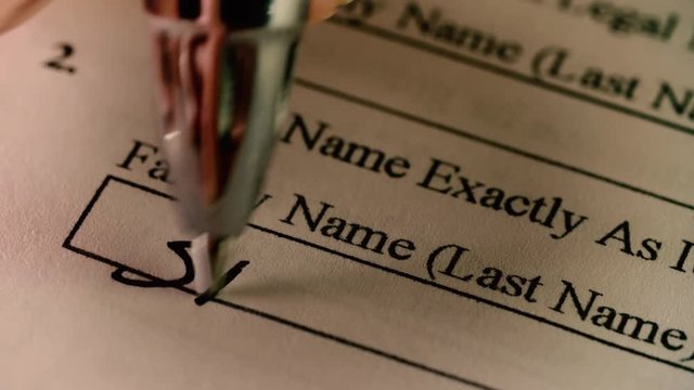 A pen writes in a family / last name on a census or US immigration document