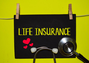 A stethoscope and blackboard with word LIFE INSURANCE on top of yellow background. Medical, health and education concepts