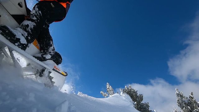 a man on a snowmobile rides beautifully on a snow inflator in the valley. on the background of snow and blue sky with clouds. super slow motion video with splashes and swirls of snow
