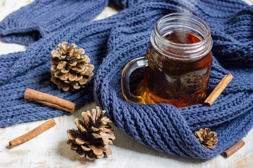 Autumn still life. cup of tea, Scarf and cinnamon sticks on wooden background.