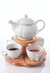 set for tea drinking in a teapot and jam in cups on a wooden stand, on a white background