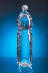 transparent water in plastic bottles on a blue background, plastic containers