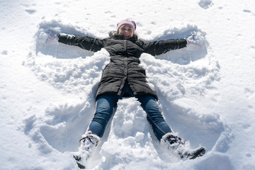 Fototapeta na wymiar happy young woman lying on snow fur in wintertime. Young happy woman kidding on snow in winter day.
