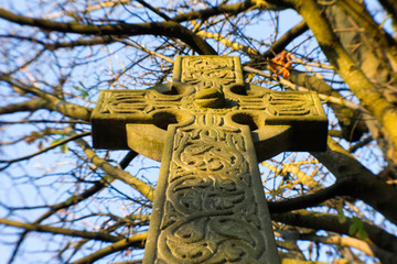 A celtic cross glowing  in the light of an Autumn sunset .