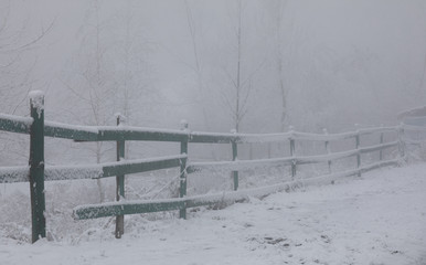 rustic fence in the winter in the fog