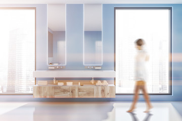 Double sink in blue bathroom interior, woman