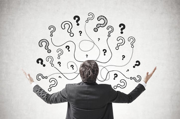 Businessman with hands in air, question marks