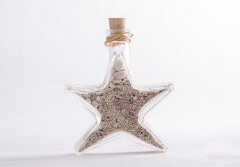 Glass bottle in the shape of a star with sand from beach