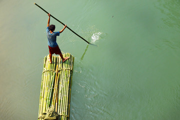  people rowing on bamboo raft in asian river 