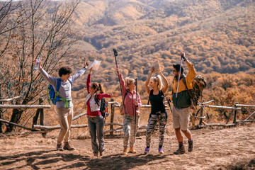 Happy hikers standing on the glade and cheering.