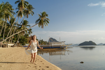 Obraz premium Girl in white dress running along the beach El Nido in the Philippines.