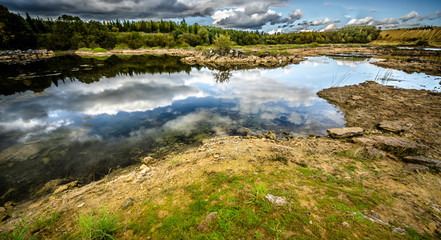 Sandy hills. Lake in the Sandy canyon. Warm colors background. Yellow sandstone textured mountain, white thin sand dune, bright sky. Sunshine landscape