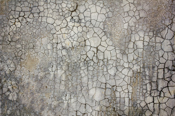 an old concrete wall with a lot of black cracks. cracked surface of the concrete wall. rough texture.
