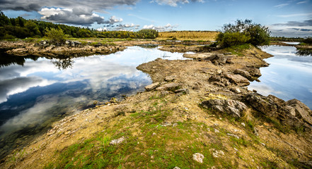 Sandy hills. Lake in the Sandy canyon. Warm colors background. Yellow sandstone textured mountain, white thin sand dune, bright sky. Sunshine landscape