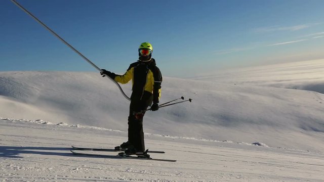 Skier using t bar ski drag lift at mountain slope
