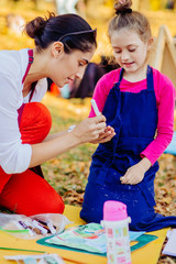 Vertical of mother helping and teaching drawing school girl elementary age. Open air activity for...