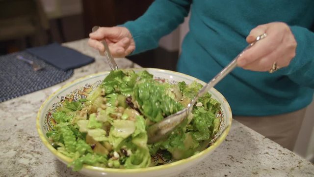 Woman Tossing Salad in Bowl with Mixed Ingredients