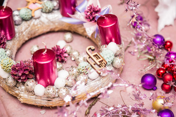Obraz na płótnie Canvas Christmas decoration round wreath, shiny accessories, candles and cones, pink, silver, on pink wrapping paper