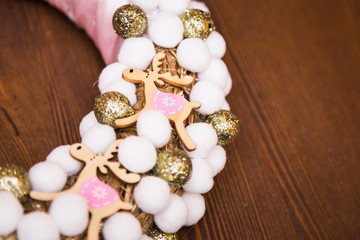 Christmas decoration wreath, accessories deers, golden, pink, white and silver balls, on a wooden table, closeup