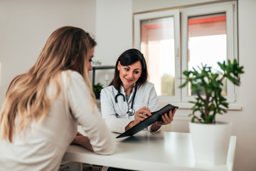 Young beautiful female doctor smiling to patient while consulting her