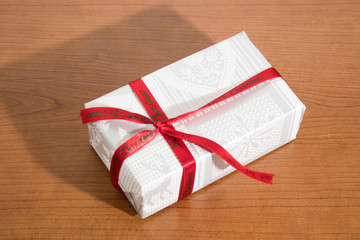 White christmas gift with red ribbon on a wood table