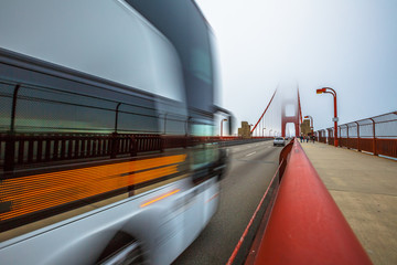Bus crossing Golden Gate Bridge from Presidio Pacific point to the north. Motion blur effect. San Francisco, California, United States. Typical fog in summertime.