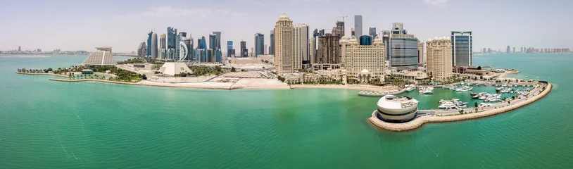 Fotobehang The skyline of Doha, Qatar. Modern rich middle eastern city of skyscrapers, aerial view in good weather, midday, during hot dry summer, with view of marina and beach of Persian Gulf/Arabian Gulf © Dmitry