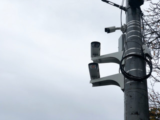 Cameras on the road pole. Three CCTV surveillance cameras on a pole. City cctv security surveillance camera system attached on the traffic light pole with gray sky background.