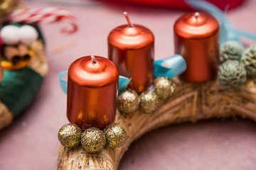 Christmas decoration round wreath, shiny accessories, candles and cones, golden, balls, on pink wrapping paper, creating process